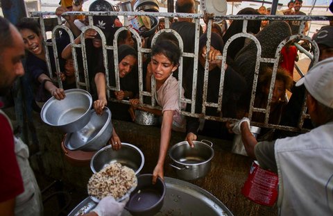 Anak-anak Palestina menunggu makanan di dapur amal di daerah Mawasi, Khan Yunis, Jalur Gaza Selatan, Selasa (22/07/2025).<br />AFP
