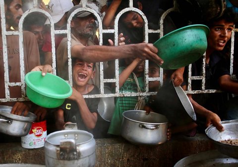 Anak-anak Palestina menunggu makanan di dapur amal di daerah Mawasi, Khan Yunis, Jalur Gaza Selatan, Selasa (22/07/2025).<br />AFP