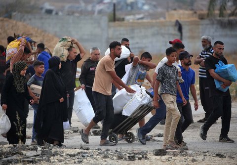 Warga Gaza membawa paket bantuan bahan  makanan dari Yayasan Kemanusiaan Gaza (GHF), sebuah kelompok bantuan swasta yang didukung AS, di Jalur Gaza bagian tengah, Minggu (08/08/2025).