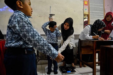 Petugas Pusat Kesehatan Masyarakat (Puskesmas) memeriksa kesehatan murid saat kegiatan Cek Kesehatan Gratis (CKG) di sekolah Madrasah Ibtidaiyah Negeri 6 Banda Aceh, Aceh, Rabu (23/07/2025).