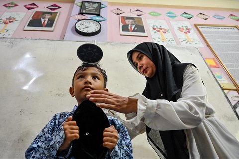 Petugas Pusat Kesehatan Masyarakat (Puskesmas) memeriksa kesehatan murid saat kegiatan Cek Kesehatan Gratis (CKG) di sekolah Madrasah Ibtidaiyah Negeri 6 Banda Aceh, Aceh, Rabu (23/07/2025).