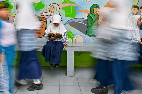 Seorang siswa menunggu sambil membaca saat  kegiatan Cek Kesehatan Gratis (CKG) di sekolah Madrasah Ibtidaiyah Negeri 6 Banda Aceh, Aceh, Rabu (23/07/2025)