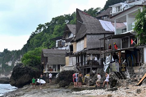 Wisatawan beraktivitas di depan restoran yang dibongkar di Pantai Bingin, Desa Pecatu, Kabupaten Badung, Bali, Rabu (23/07/2025).