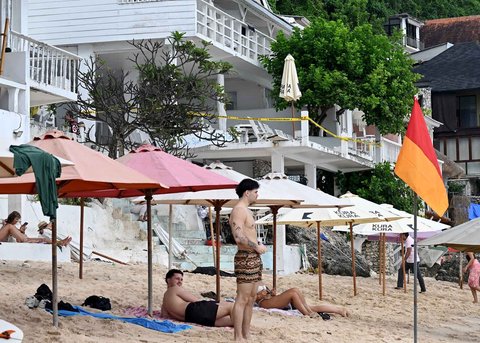 Wisatawan beraktivitas di depan restoran yang dibongkar di Pantai Bingin, Desa Pecatu, Kabupaten Badung, Bali, Rabu (23/07/2025).