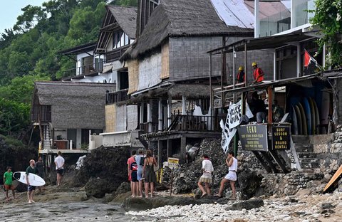 Wisatawan beraktivitas di depan restoran yang dibongkar di Pantai Bingin, Desa Pecatu, Kabupaten Badung, Bali, Rabu (23/07/2025).