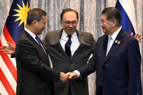 Perdana Menteri Kamboja Hun Manet (kiri) dan Penjabat Perdana Menteri Thailand Phumtham Wechayachai (kanan) berjabat tangan disaksikan Perdana Menteri Malaysia Anwar Ibrahim setelah perundingan perundingan gencatan senjata antara Thailand dan Kamboja di Putrajaya, Malaysia, Senin (28/07/2025).