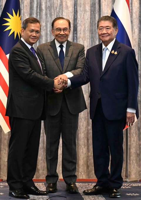 Perdana Menteri Kamboja Hun Manet (kiri) dan Penjabat Perdana Menteri Thailand Phumtham Wechayachai (kanan) berjabat tangan bersama Perdana Menteri Malaysia Anwar Ibrahim setelah perundingan perundingan gencatan senjata antara Thailand dan Kamboja di Putrajaya, Malaysia, Senin (28/07/2025).