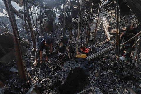 Sejumlah pedagang mengais puing dan sisa barang dagangan yang hangus terbakar di Pasar Taman Puring, Jakarta Selatan, Selasa (29/7/2025).