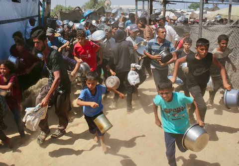 Anak-anak Palestina menunggu makanan di dapur amal di daerah Mawasi, Khan Yunis, Jalur Gaza Selatan, Selasa (22/07/2025).<br />AFP