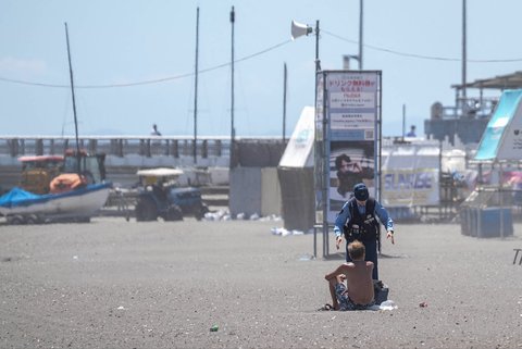 Seorang petugas polisi meminta seorang pria untuk mengungsi dari pantai yang kosong karena peringatan tsunami di kota Fujisawa, Prefektur Kanagawa, Jepang, Rabu (30/07/2025).