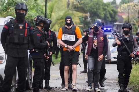 Petugas mengawal warga negara Australia yang diidentifikasi berinisial PT untuk mengikuti rekontruksi kepolisian di Badung, Bali, Rabu (30/07/2025).<br />)