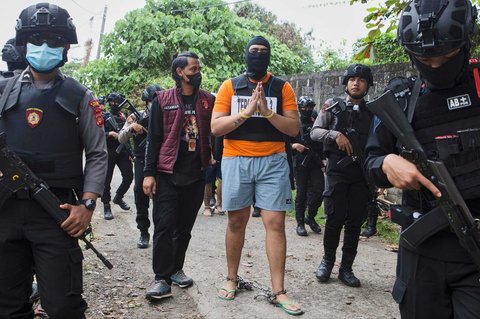 Petugas mengawal warga negara Australia yang diidentifikasi berinisial DJF untuk  mengikuti rekontruksi kepolisian di Badung, Bali, Rabu (30/07/2025).