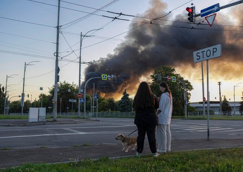 Warga berjalan  dengan anjingnya saat asap mengepul di ibu kota Ukraina, Kyiv,  Jumat (04/07/2025)