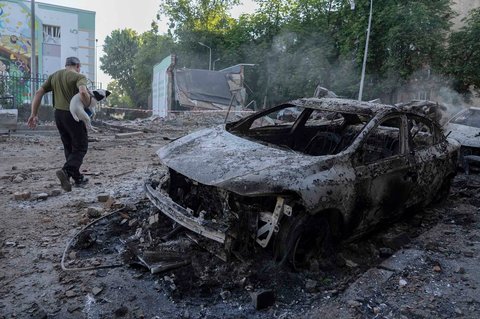 Warga berjalan  dengan anjingnya saat asap mengepul di ibu kota Ukraina, Kyiv,  Jumat (04/07/2025)