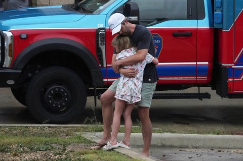 Seorang ayah memeluk anaknya usai banjir bandang di Kerrville, Texas,  Jumat,  (04/07/2025).