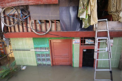 Warga beraktifitas saat banjir merendam pemukiman di Jalan Pirus, Kelurahan Bidara Cina, Jatinegara, Jakarta Timur, Minggu (06/07/2025).