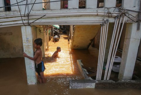 Warga beraktifitas saat banjir merendam pemukiman di Jalan Pirus, Kelurahan Bidara Cina, Jatinegara, Jakarta Timur, Minggu (06/07/2025).