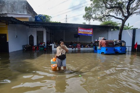 Warga melewati banjir yang merendam Kampung Cantiga, Petir, Cipondoh, Kota Tangerang, pada Selasa (8/7/2025). Kawasan Tangerang saat ini dikepung banjir akibat meluapnya Kali Angke. Sementara, ketinggian banjir yang merendam Kampung Cantiga mencapai 1,8 meter.