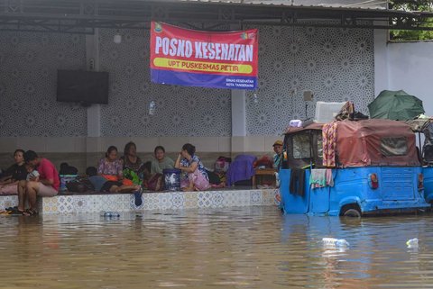 Sejumlah warga terdampak banjir mengungsi di sebuah posko kesehatan di Kampung Cantiga, Petir, Cipondoh, Kota Tangerang, pada Selasa (8/7/2025). Kawasan Tangerang saat ini dikepung banjir akibat meluapnya Kali Angke. Sementara, ketinggian banjir yang merendam Kampung Cantiga mencapai 1,8 meter.