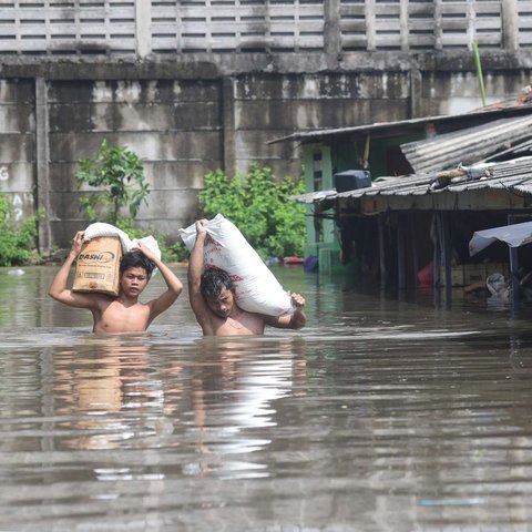 Warga melewati banjir yang merendam Kampung Cantiga, Petir, Cipondoh, Kota Tangerang, pada Selasa (8/7/2025). Kawasan Tangerang saat ini dikepung banjir akibat meluapnya Kali Angke. Sementara, ketinggian banjir yang merendam Kampung Cantiga mencapai 1,8 meter.