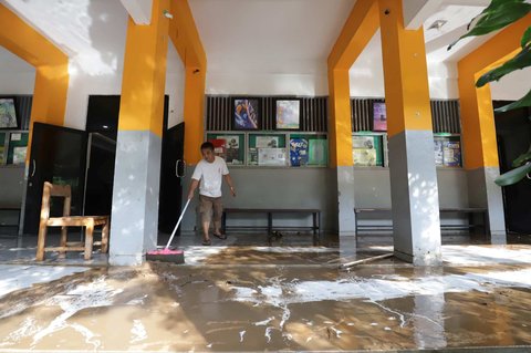 Petugas membersihkan ruang kelas setelah banjir merendam SMAN 60 Jakarta di kawasan Duren Tiga, Jakarta, Selasa (8/7/2025).