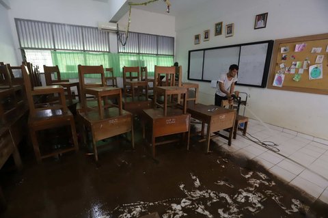 Petugas membersihkan ruang kelas setelah banjir merendam SMAN 60 Jakarta di kawasan Duren Tiga, Jakarta, Selasa (8/7/2025).