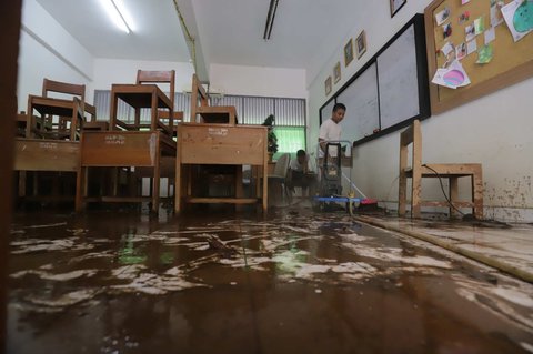 Petugas membersihkan ruang kelas setelah banjir merendam SMAN 60 Jakarta di kawasan Duren Tiga, Jakarta, Selasa (8/7/2025).
