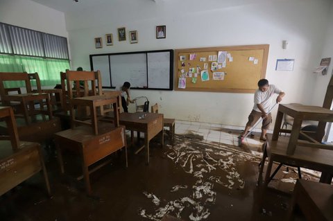 Petugas membersihkan ruang kelas setelah banjir merendam SMAN 60 Jakarta di kawasan Duren Tiga, Jakarta, Selasa (8/7/2025).