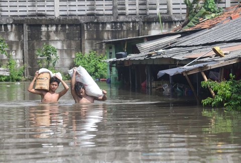 Warga melewati banjir yang merendam Kampung Cantiga, Petir, Cipondoh, Kota Tangerang, pada Selasa (8/7/2025). Kawasan Tangerang saat ini dikepung banjir akibat meluapnya Kali Angke. Sementara, ketinggian banjir yang merendam Kampung Cantiga mencapai 1,8 meter.