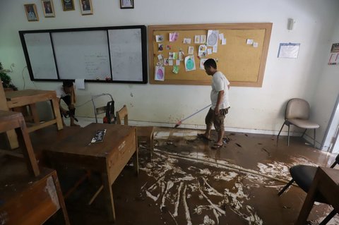 Petugas membersihkan ruang kelas setelah banjir merendam SMAN 60 Jakarta di kawasan Duren Tiga, Jakarta, Selasa (8/7/2025).