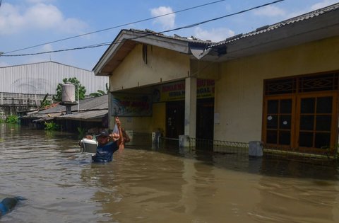 Warga melewati banjir yang merendam Kampung Cantiga, Petir, Cipondoh, Kota Tangerang, pada Selasa (8/7/2025). Kawasan Tangerang saat ini dikepung banjir akibat meluapnya Kali Angke. Sementara, ketinggian banjir yang merendam Kampung Cantiga mencapai 1,8 meter.