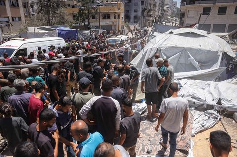 Warga memeriksa lokasi serangan Israel di samping tenda yang menampung warga Palestina yang mengungsi di Kota Gaza, Selasa (08/07/2025).