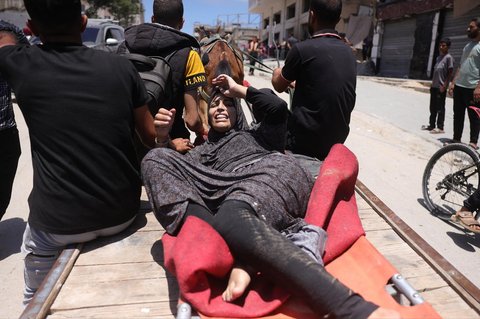 Seorang wanita terluka  dievakuasi di lokasi serangan Israel di samping tenda yang menampung menampung warga Palestina yang mengungsi di Kota Gaza,