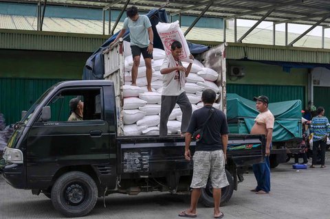 Pekerja menyiapkan pesanan beras  pelanggan di pasar induk  beras  Cipinang, Jakarta, Rabu (09/07/2025).  AFP/ Bay Ismoyo
