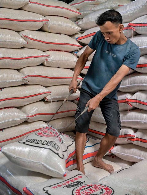 Pekerja menyiapkan pesanan beras  pelanggan di pasar induk  beras  Cipinang, Jakarta, Rabu (09/07/2025).  AFP/ Bay Ismoyo