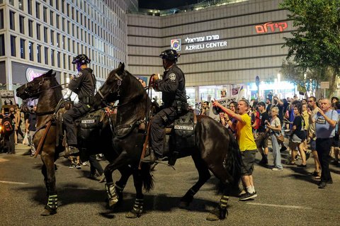 Seorang pengunjuk rasa berhadapan dengan polisi Israel berkuda saat berupaya membubarkan orang-orang yang berkumpul untuk demonstrasi di luar kantor pusat Kementerian Pertahanan di Tel Aviv, Israel, Sabtu (09/08/2025) malam.