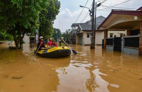 RRelawan mengevakuasi warga dengan perahu karet saat banjir di kawasan Villa Pamulang, Depok, jawa Barat, Minggu (10/08/2025).