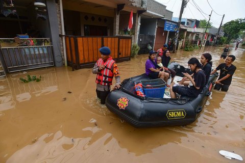 Angggota Brimob Polda Metro Jaya mengevakuasi warga menggunakan perahu karet setelah banjir  merendam kawasan Perumahan Villa Pamulang, Kelurahan Pondok Petir, Kecamatan Bojongsari, Kota Depok, Jawa Barat, Minggu (10/8/2025).