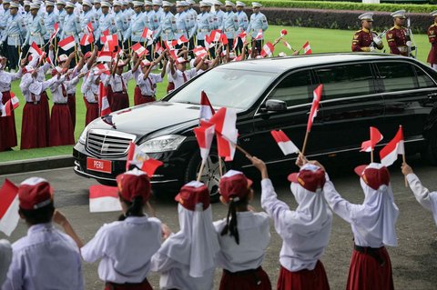 Anak-anak mengibarkan bendera kedua negara saat kendaraan Presiden Peru, Dina Boluarte, tiba di Istana Merdeka, Jakarta, Senin (11/08/2025).