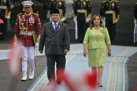 Presiden Indonesia Prabowo Subianto bersama Presiden Peru Dina Boluarte memeriksa barisan kehormatan presiden di tengah anak-anak yang mengibarkan bendera kedua negara di Istana Merdeka, Jakarta, Senin (11/08/2025).