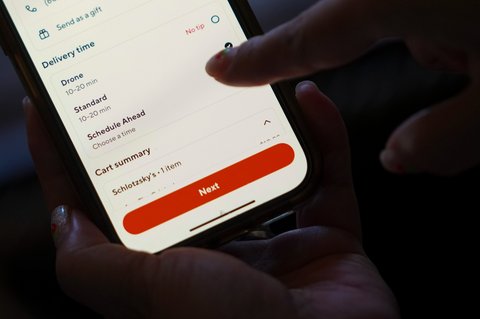 Pelanggan memilih opsi pengiriman drone saat memesan melalui aplikasi DoorDash di ponselnya di Frisco, Texas, AS ,Kamis (31/07/2025).