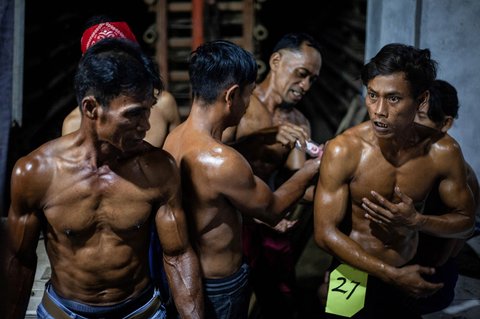 Pekerja pabrik genteng saling mengolesi tubuh mereka dengan oli sebelum mengikuti kompetisi binaraga tradisional di sebuah pabrik genteng di Jatiwangi, Jawa Barat (11/08/2025