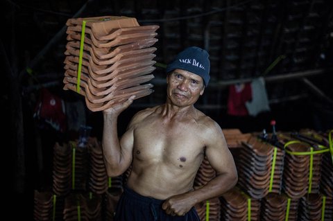 Pekerja pabrik genteng berpose sambil melakukan pemanasan sebelum mengikuti kompetisi binaraga tradisional di sebuah pabrik genteng di Jatiwangi, Jawa Barat (11/08/2025
