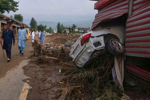 Warga berjalan melewati toko-toko yang rusak akibat banjir bandang di pinggiran Pir Baba, distrik Buner, di barat laut Pakistan, Sabtu (16/08/2025).