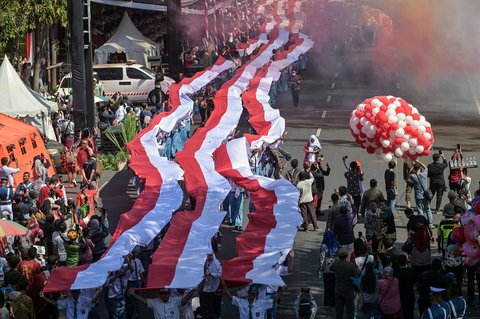 Ribuan pelajar dari berbagai sekolah di Surabaya membentangkan bendera merah putih sepanjang 14. 905 meter di di Jalan Gubernur Suryo Surabaya, Minggu (17/08/2025).