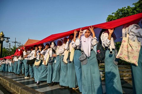Ribuan pelajar dari berbagai sekolah di Surabaya membentangkan bendera merah putih sepanjang 14. 905 meter di di Jalan Gubernur Suryo Surabaya, Minggu (17/08/2025).