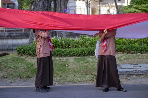 Pelajar dari berbagai sekolah di Surabaya membentangkan bendera merah putih sepanjang 14. 905 meter di di Jalan Gubernur Suryo Surabaya, Minggu (17/08/2025).