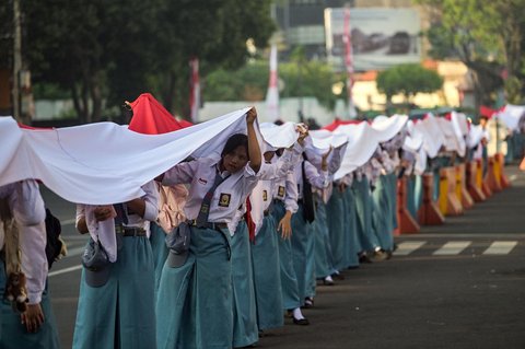 Ribuan pelajar dari berbagai sekolah di Surabaya membentangkan bendera merah putih sepanjang 14. 905 meter di di Jalan Gubernur Suryo Surabaya, Minggu (17/08/2025).