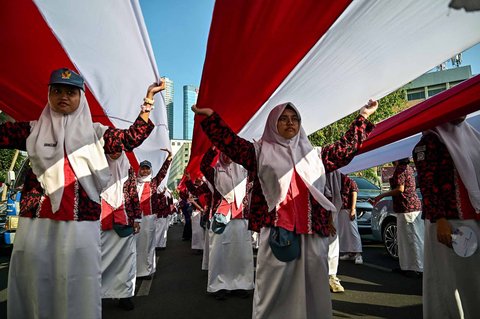 Ribuan pelajar dari berbagai sekolah di Surabaya membentangkan bendera merah putih sepanjang 14. 905 meter di di Jalan Gubernur Suryo Surabaya, Minggu (17/08/2025).