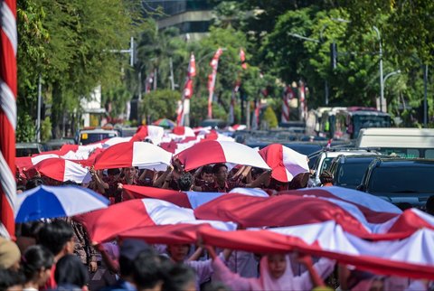 Ribuan pelajar dari berbagai sekolah di Surabaya membentangkan bendera merah putih sepanjang 14. 905 meter di di Jalan Gubernur Suryo Surabaya, Minggu (17/08/2025).